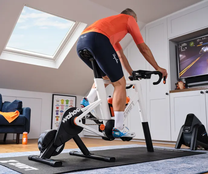 A rider out of the saddle on a Zwift Ride frame paired with a KICKR trainer