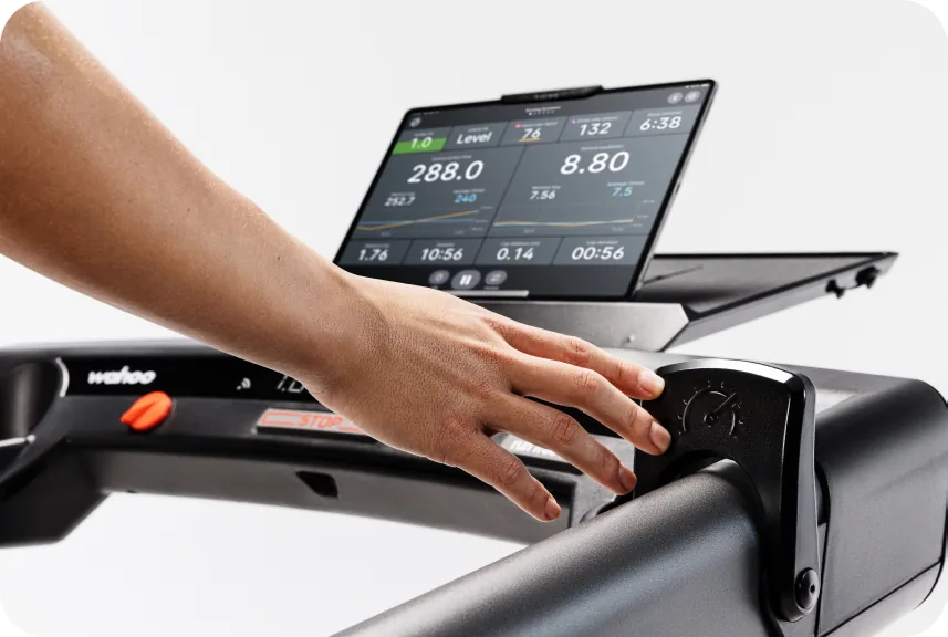 Runner on KICKR RUN following a paced workout on screen